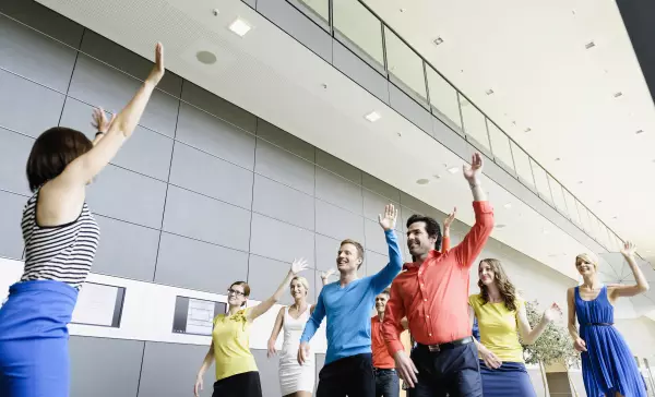 Business Leute tanzen zum Warm-Up im Büro mit einem Moderator