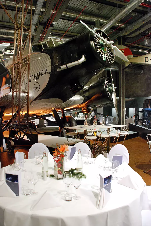 Blog BerlinMeetings Museen als Event-Location Runde Tische im Luftfahrtbereich des Technikmuseums mit Flugzeug im Hinterg