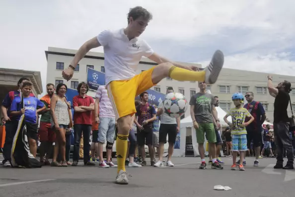 Foto: Junger Mann kickt Fußball, umgeben von einer Menschentraube als Jung und Alt