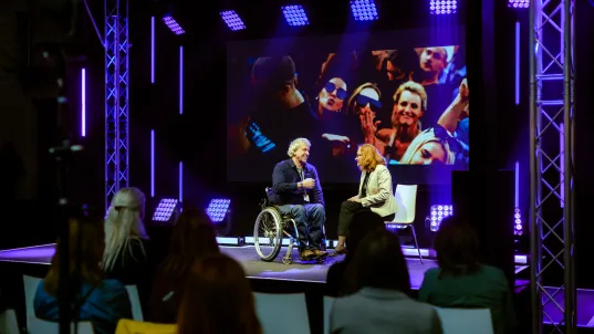 Two people are on stage during an evening programme.
