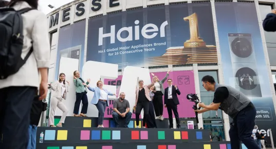 Menschen jubeln auf einer Bühne vor dem Eingang der Messe Berlin, Fotograf macht ein Bild.