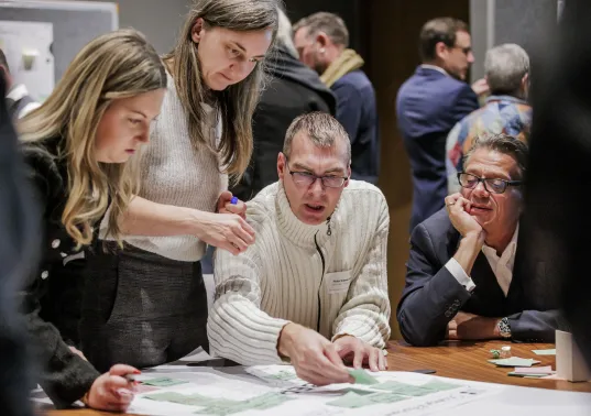 Vier Personen diskutieren konzentriert um einen Tisch mit Plänen.