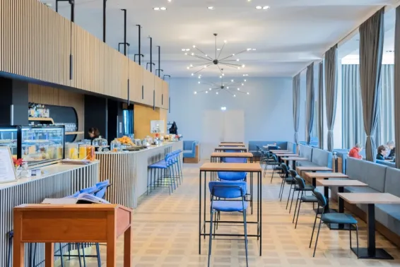 Helles, modernes Café mit blauen Stühlen und großen Fenstern