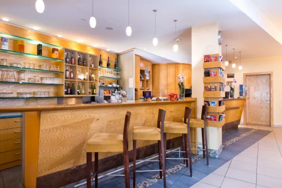 Leere moderne Bar mit Holztheke, Regalen und drei Barhockern.