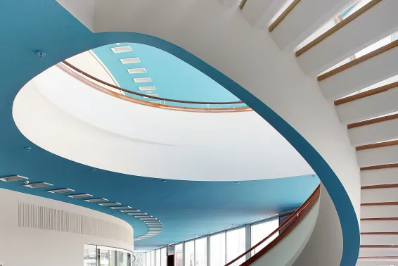 Moderne Wendeltreppe mit blauem Deckenelement und viel Tageslicht