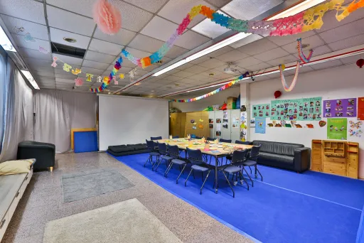 Bunte Kita mit Tischgruppe, Girlanden und Spielen an den Wänden