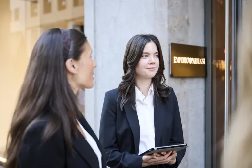 Zwei Frauen in schwarzen Blazern stehen vor einem Laden, eine hält ein Tablet – Eventpersonal und Promotionteam im Einsatz.