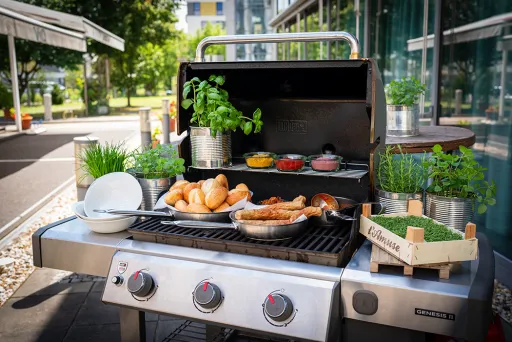 Eisstockpaket Sommer mit Grill & Würstchen, Brötchen, frischen Kräutern und Saucen im Freien.