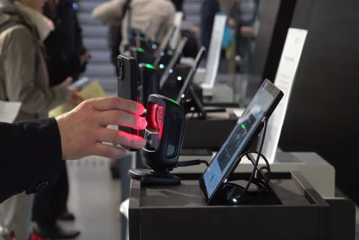 Selbstregistrierung am Einlass eines Kongresses: Teilnehmende scannen ihre Unterlagen an modernen Check-in-Stationen mit Tablets und Scannern.