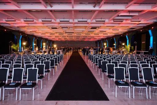 Großer Konferenzsaal mit vielen leeren Stuhlreihen und bunter Deckenbeleuchtung.