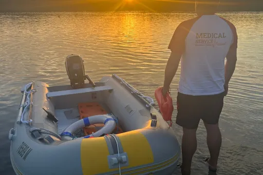 Mann steht neben Schlauchboot im seichten Wasser bei Sonnenuntergang.