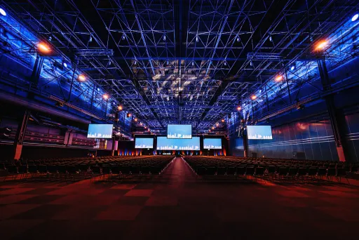 Große Halle, blau beleuchtet mit mehreren beleuchteten Displays, welche von der Decke hängen.