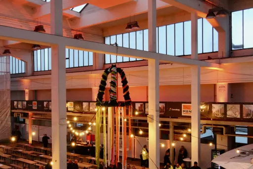 Große, helle Halle mit vielen Menschen, Lichterketten und festlicher Dekoration.