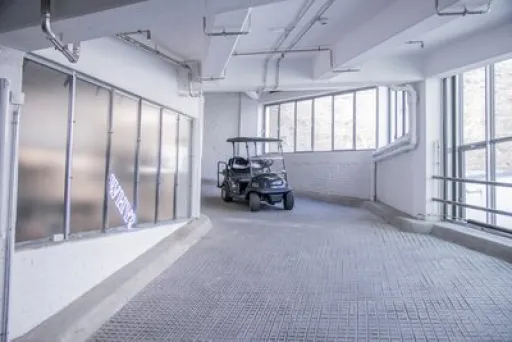 Golfcart steht in heller Tiefgarage mit großen Fenstern.