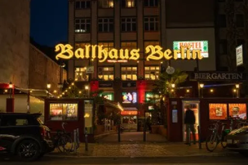 Leuchtendes Ballhaus Berlin bei Nacht, umgeben von Lichtern und Fahrrädern.
