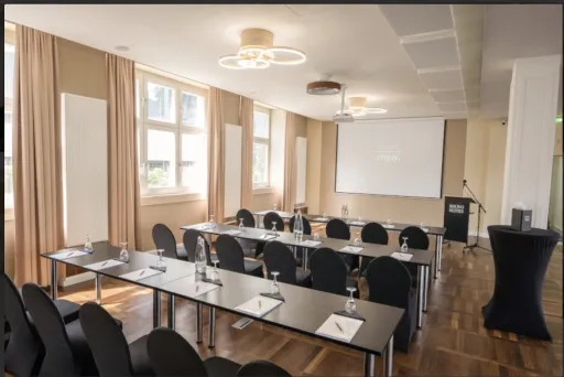 Heller Seminarraum mit Tischen, Stühlen, Beamer 