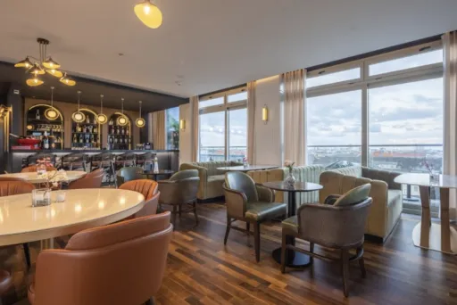 Modernes Café mit großen Fenstern, gemütlichen Sesseln und Blick auf die Stadt.