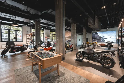 Modernes Geschäft mit Motorrädern, Kickertisch und großen Fenstern, helle Atmosphäre