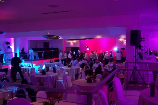 Viele Menschen sitzen an Tischen in lilanem Licht in einem großen Raum