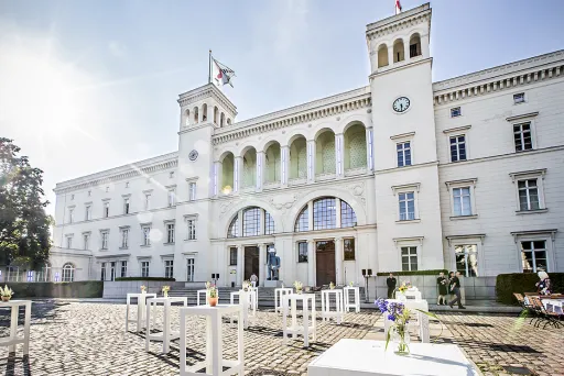 Helles Schlossgebäude mit Türmen, Sonnenschein und weißen Tischen im Innenhof