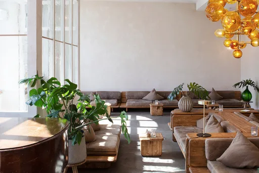 Die lichtdurchflutete Lobby vom Michelberger Hotel mit Ledersofas, Pflanzen und Piano