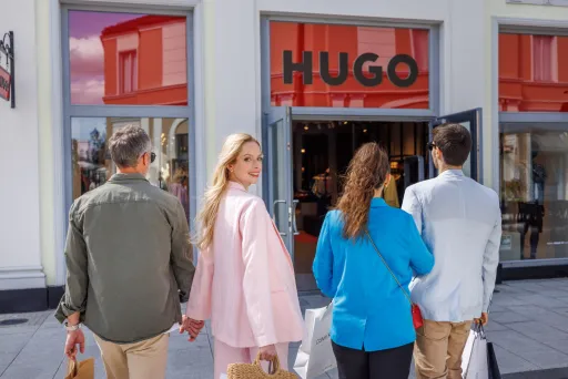 Vier Personen mit Einkaufstaschen vor dem HUGO-Geschäft.