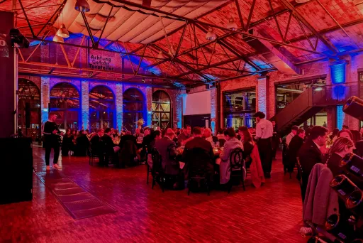 eine große Gruppe sitzt an mehreren Rundtischen gemeinsam in der classic remise