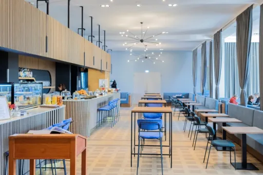 Helles, modernes Café mit blauen Stühlen und großen Fenstern