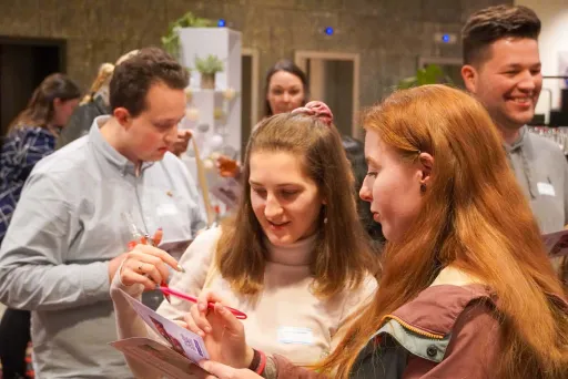 Mehrere junge Erwachsene unterhalten sich und lachen bei einem Treffen drinnen.