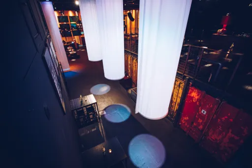 Leerer, modern beleuchteter Veranstaltungsraum mit weißen Stoffbahnen und roten Containern.