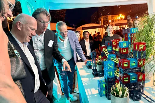 Der Regierende Bürgermeister von Berlin betrachtet bunte Modelle auf einem Tisch beim Hoffest