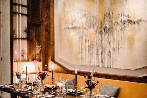 Elegant gedeckter Esstisch mit Kerzen, Bild mit abstrakter Kunst an der Wand.