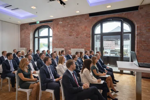 Männer und Frauen im Anzug sitzen aufmerksam in einem modernen Konferenzraum.