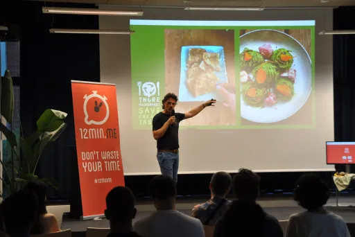 Mann hält Vortrag vor Publikum, zeigt auf Essensbilder auf einer Leinwand.