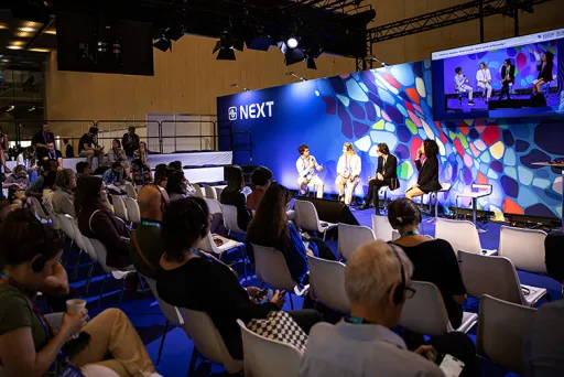 Podiumsdiskussion mit vier Personen auf einer Bühne vor interessiertem Publikum.