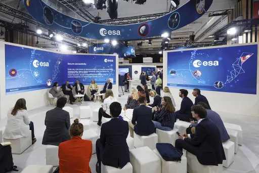 Menschen sitzen im Kreis bei einer Diskussionsrunde auf einer Messe der ESA.