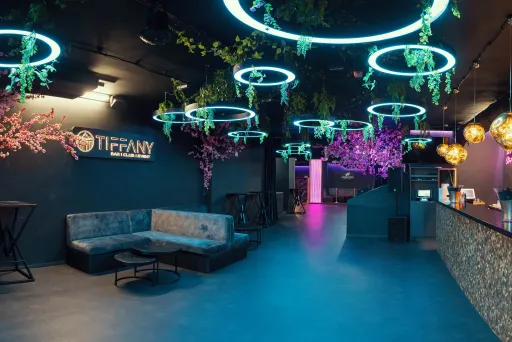 Modern eingerichtete Bar mit Neonlichtern, Pflanzen und gemütlichen Sitzbereichen.