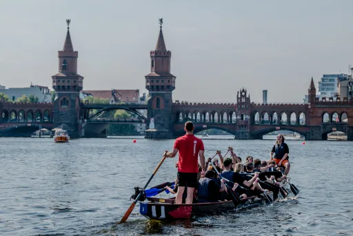 Drachenboot mit Team auf der Spree, im Hintergrund die Oberbaumbrücke in Berlin.