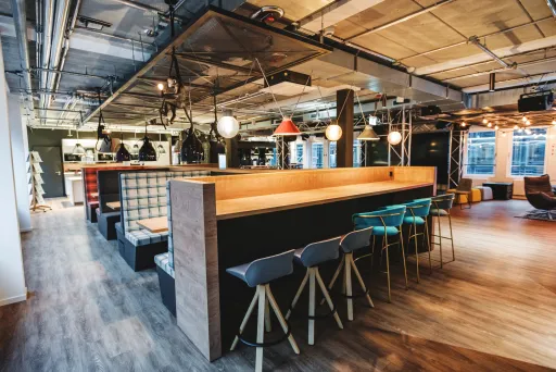 Moderne Veranstaltungsfläche mit Sitzbänken, Barhockern und stilvoller Beleuchtung.