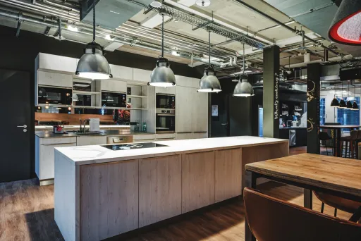 Moderner Küchenbereich mit großer Kochinsel, Hängelampen und Holzboden
