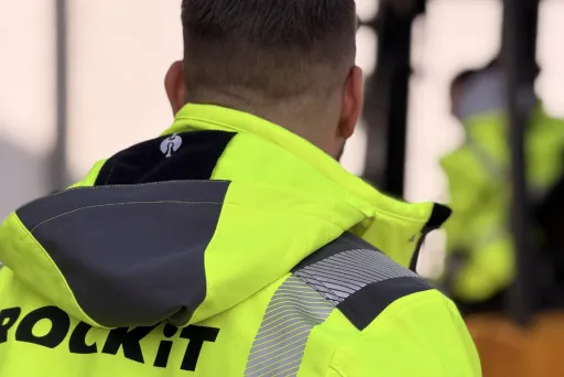 Mann in gelber Warnjacke vor Gabelstapler im Freien