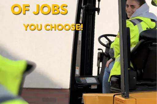 Frau im gelben Gabelstapler, trägt Warnweste, blickt zur Kamera.