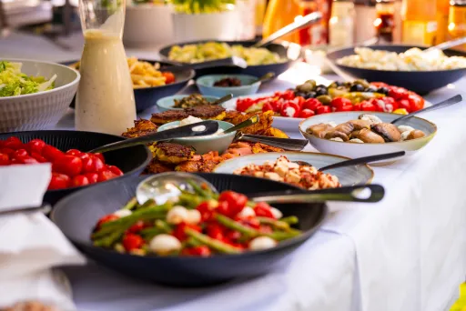 Verschiedene bunte Vorspeisen auf einem Buffet mit Salaten und Gemüse.