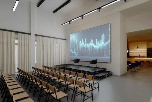 Moderner Konferenzraum mit Reihen aus Stühlen, Bühne und großem Bildschirm