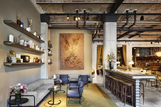 Modernes Hotellobby mit gemütlicher Sitzecke, großen Gemälden und stilvoller Bar.