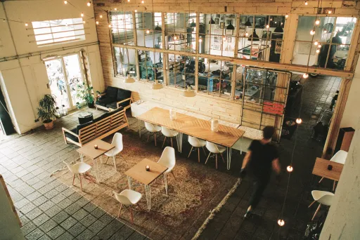 Heller, moderner Coworking-Space mit Holztischen, Stühlen und gemütlicher Beleuchtung.