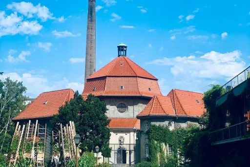 Backstein-Gebäude mit rotem Dach, Schornstein und blauem Himmel im Hintergrund