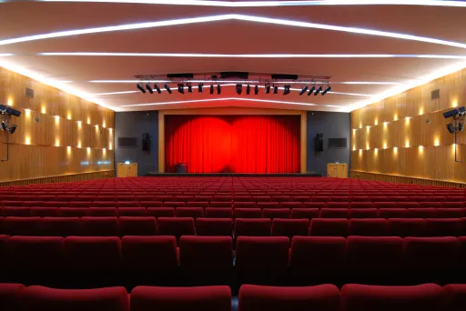Leerer Theatersaal mit roten Sitzen und rotem Vorhang auf der Bühne
