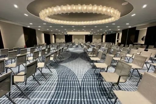 Konferenzraum mit vielen leeren Stühlen und großem, rundem Kronleuchter.