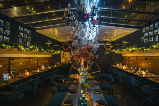 Stimmungsvoll beleuchtetes Restaurant mit festlich gedeckten Tischen und Kronleuchter.